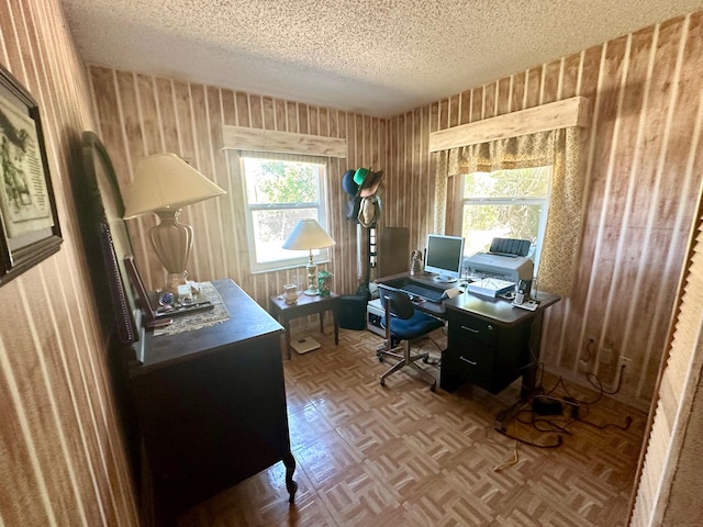 office area with a textured ceiling and wallpapered walls