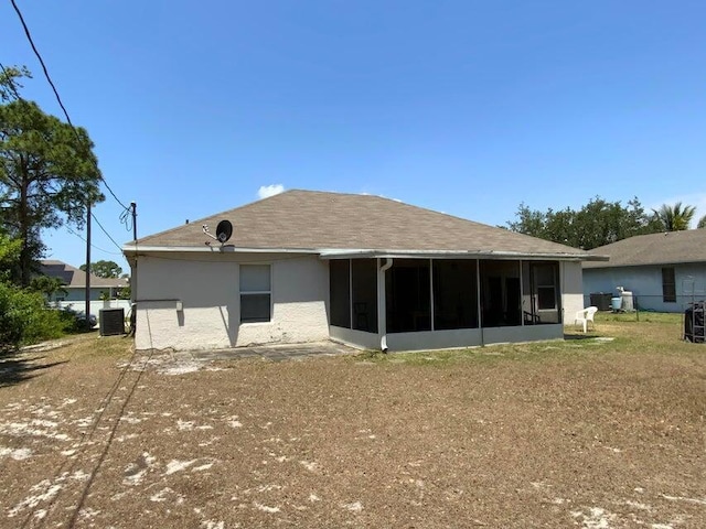 rear view of house with stucco siding, cooling unit, and a sunroom