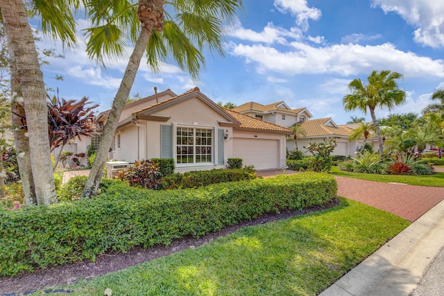 view of front of home with stucco siding, a front lawn, a garage, a tile roof, and decorative driveway