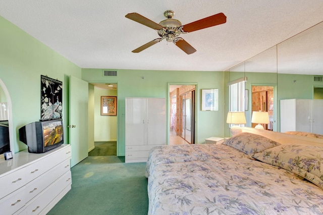 bedroom featuring visible vents, carpet floors, a textured ceiling, and ceiling fan