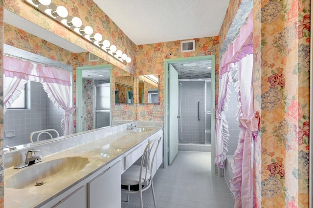 full bathroom featuring visible vents, a sink, a textured ceiling, a shower stall, and wallpapered walls