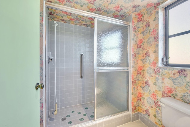 bathroom with wallpapered walls, a shower stall, and a wealth of natural light