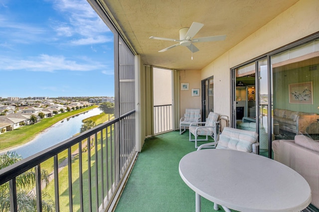 balcony with radiator, a ceiling fan, and a water view