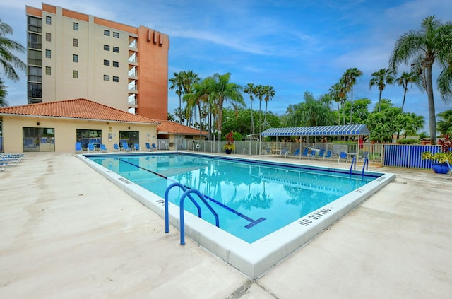 community pool with a patio and fence