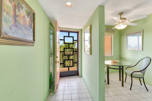 hallway featuring light tile patterned floors, baseboards, and a textured ceiling