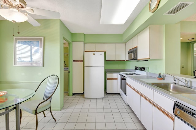 kitchen featuring visible vents, a sink, white appliances, white cabinets, and light countertops