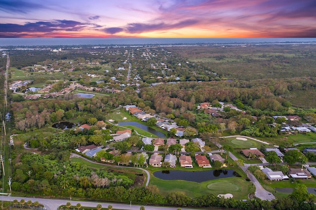 aerial view at dusk with a residential view, a view of trees, and a water view