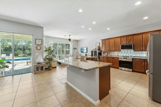 kitchen featuring a sink, light tile patterned floors, a ceiling fan, and stainless steel appliances