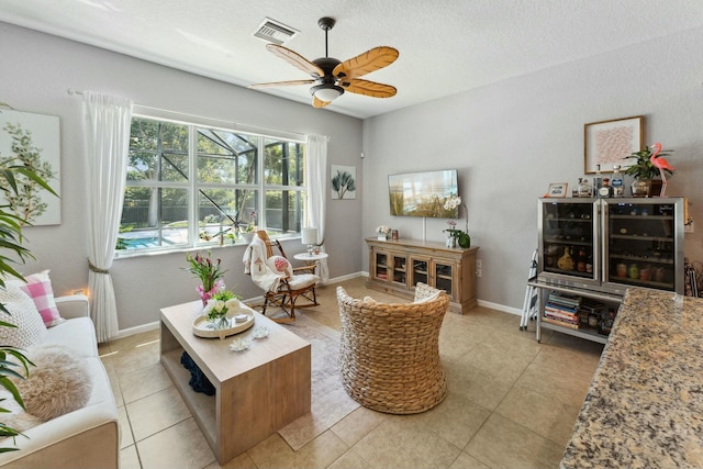 living room with visible vents, baseboards, light tile patterned floors, a textured ceiling, and a ceiling fan