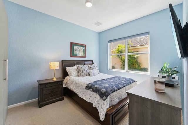 bedroom featuring visible vents, light carpet, and baseboards