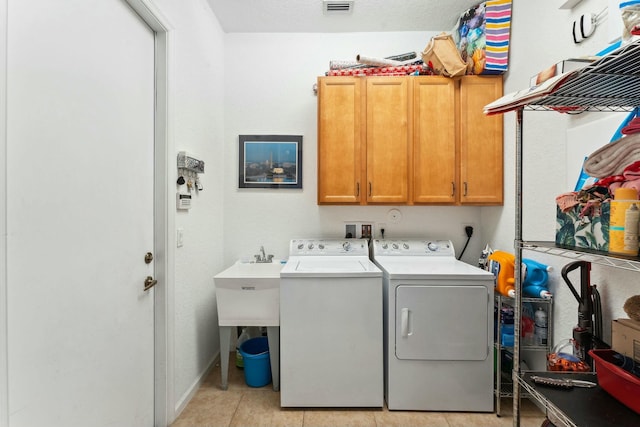 washroom featuring visible vents, cabinet space, light tile patterned flooring, and washer and clothes dryer