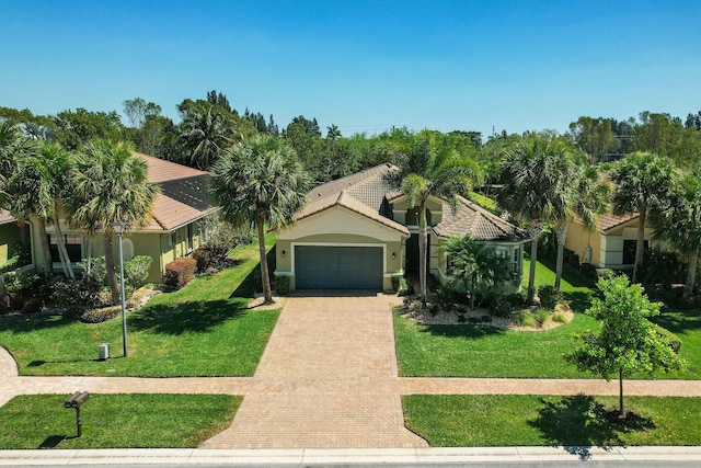 view of front of home featuring a front yard, driveway, an attached garage, stucco siding, and a tiled roof