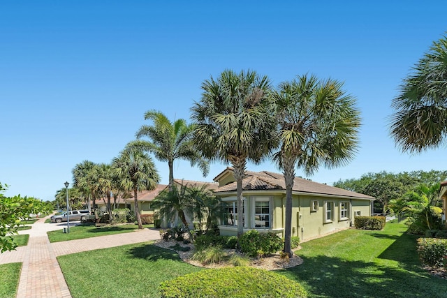 view of property exterior featuring a tile roof, a lawn, and stucco siding