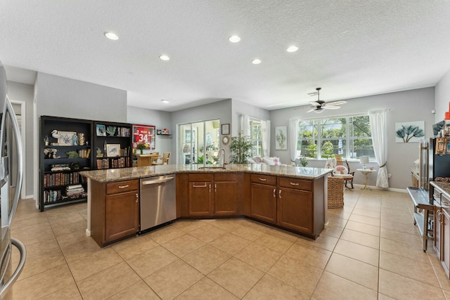 kitchen featuring light tile patterned floors, a ceiling fan, a sink, stainless steel dishwasher, and open floor plan