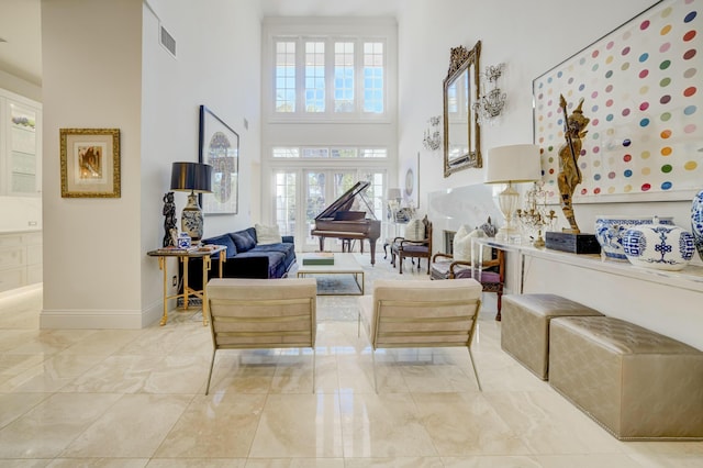 living room featuring a high ceiling, baseboards, visible vents, and a wealth of natural light