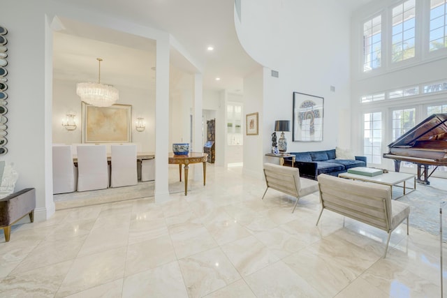 living area featuring baseboards, visible vents, a high ceiling, a notable chandelier, and marble finish floor