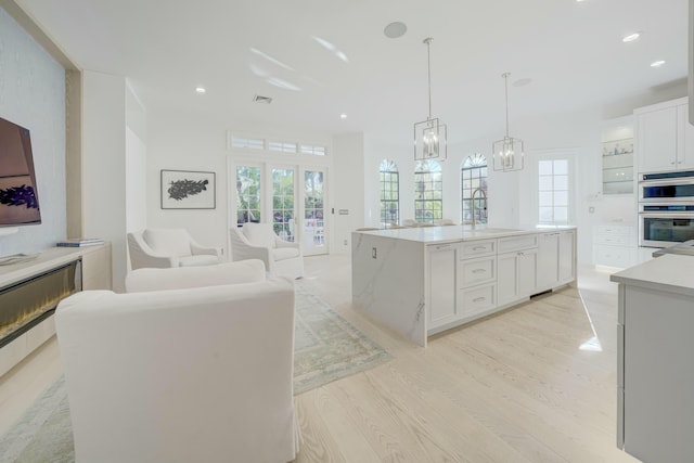 kitchen with plenty of natural light, double oven, white cabinetry, and a sink