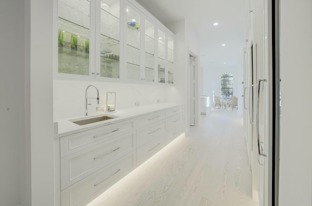 hallway featuring recessed lighting, light wood-type flooring, and a sink