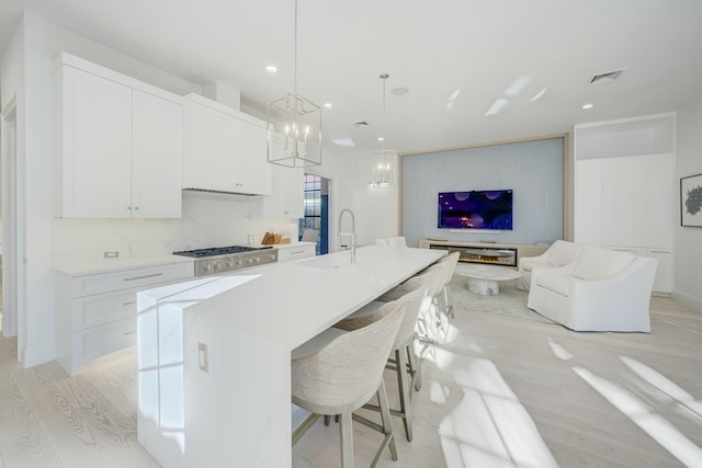 kitchen with visible vents, light wood-style flooring, white cabinetry, open floor plan, and backsplash