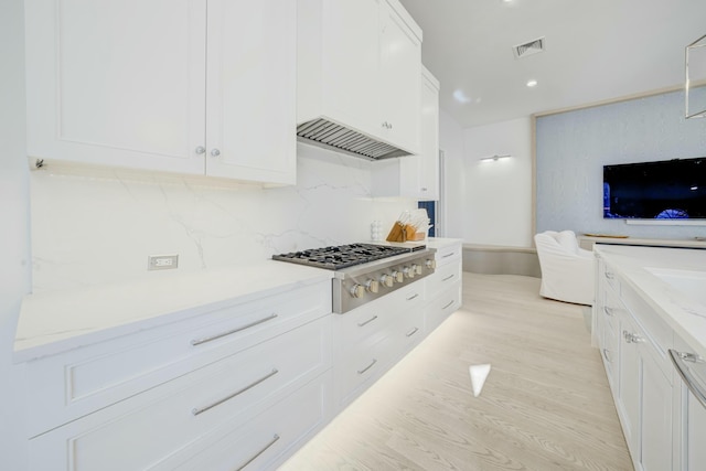 kitchen with visible vents, backsplash, gas stovetop, light wood-style floors, and white cabinets