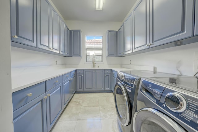 laundry room featuring a sink, light tile patterned floors, cabinet space, and washing machine and clothes dryer