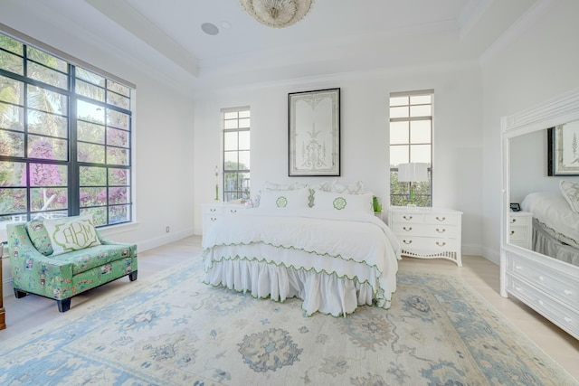 bedroom featuring a raised ceiling, wood finished floors, baseboards, and ornamental molding