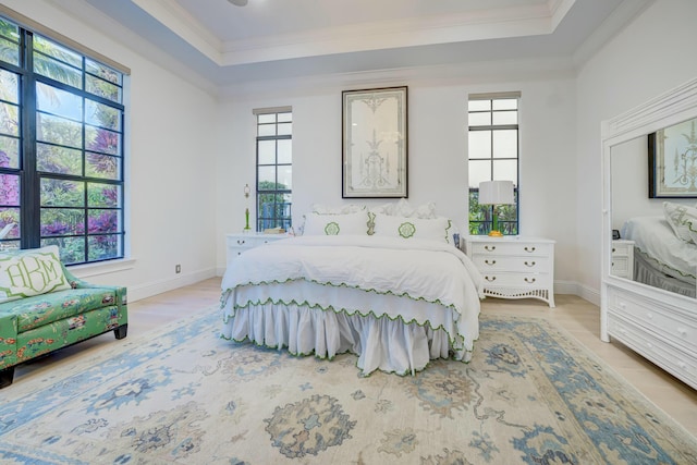 bedroom with a tray ceiling, baseboards, wood finished floors, and crown molding