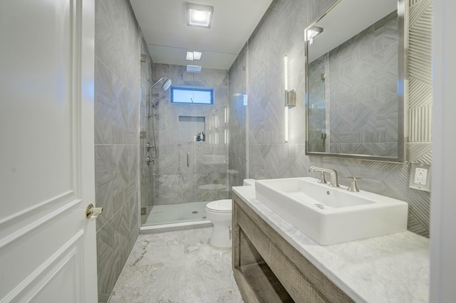 bathroom featuring toilet, marble finish floor, tile walls, a shower stall, and vanity