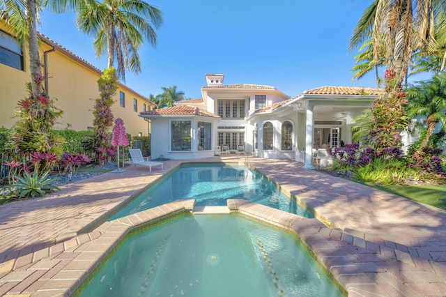 rear view of house with a patio, a pool with connected hot tub, stucco siding, french doors, and a tile roof