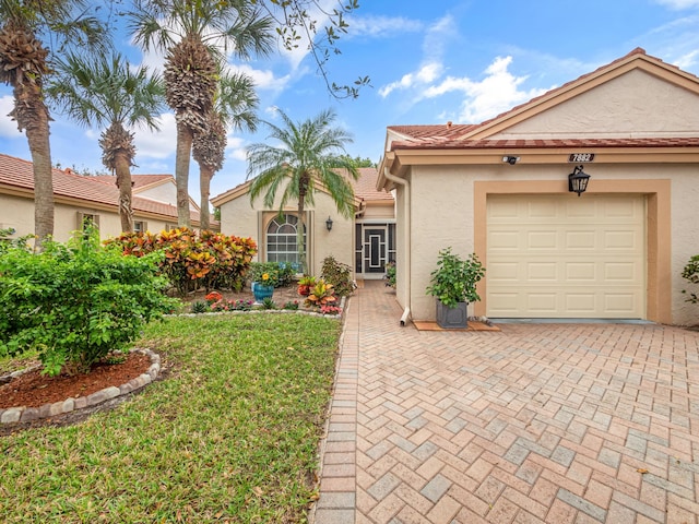 7882 Lake Sands Dr, Delray Beach, FL 33446 - view of front facade with stucco siding, decorative driveway, a garage, and a front lawn