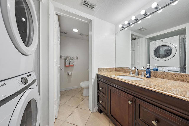 bathroom with tile patterned floors, toilet, visible vents, and stacked washer and clothes dryer