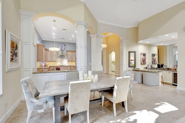 dining space with crown molding, wine cooler, decorative columns, light tile patterned floors, and arched walkways