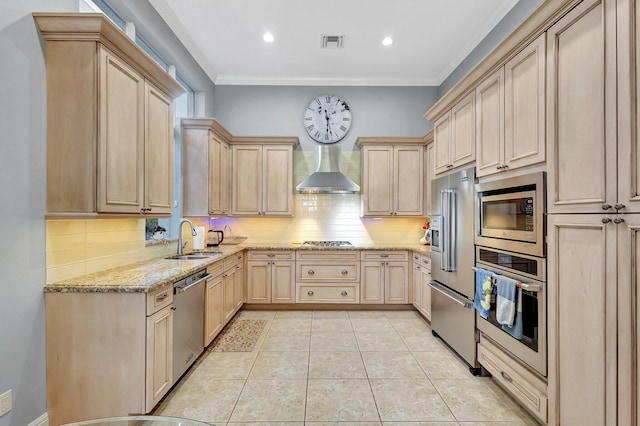 kitchen with light brown cabinets, visible vents, a sink, stainless steel appliances, and wall chimney range hood