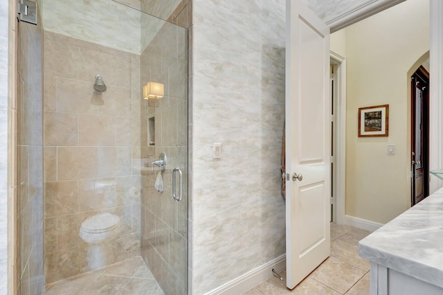 bathroom featuring tile patterned flooring, a stall shower, and baseboards