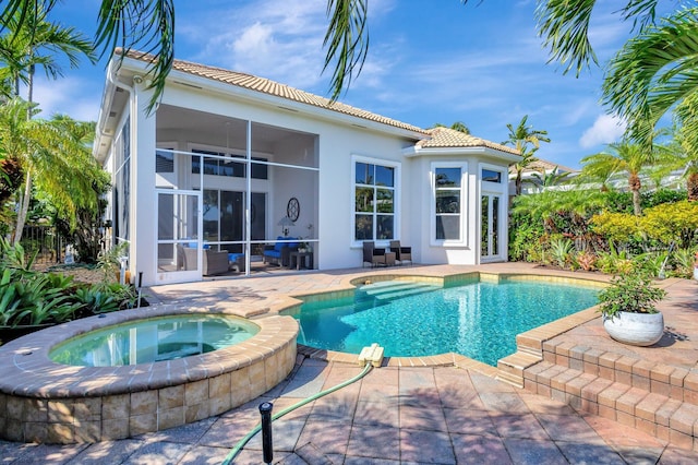 pool with a sunroom, an in ground hot tub, and a patio area