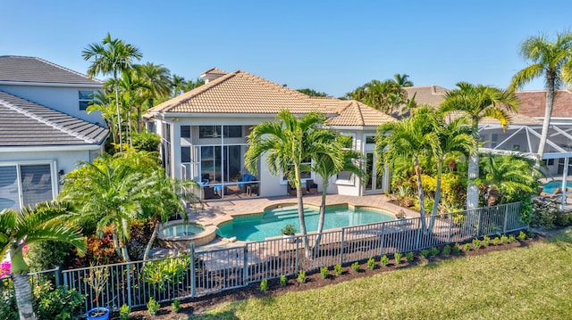 back of house featuring a tiled roof, fence, a pool with connected hot tub, and stucco siding