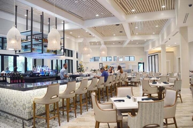 dining area with beam ceiling, a high ceiling, wood finished floors, and coffered ceiling