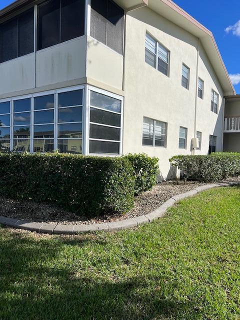 view of side of property featuring a lawn and stucco siding