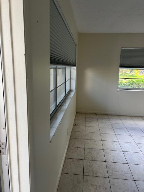 spare room with light tile patterned floors and baseboards