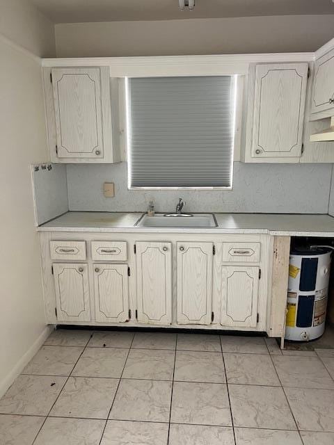 kitchen featuring baseboards, water heater, a sink, light countertops, and extractor fan