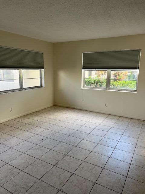 unfurnished room featuring light tile patterned floors, a healthy amount of sunlight, and a textured ceiling