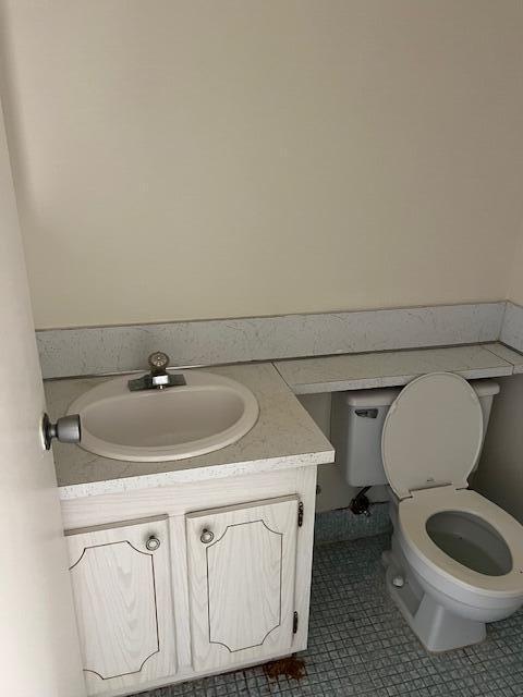 bathroom with toilet, vanity, and tile patterned flooring