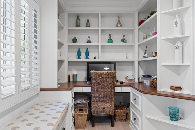 office space with built in desk, crown molding, and wood finished floors
