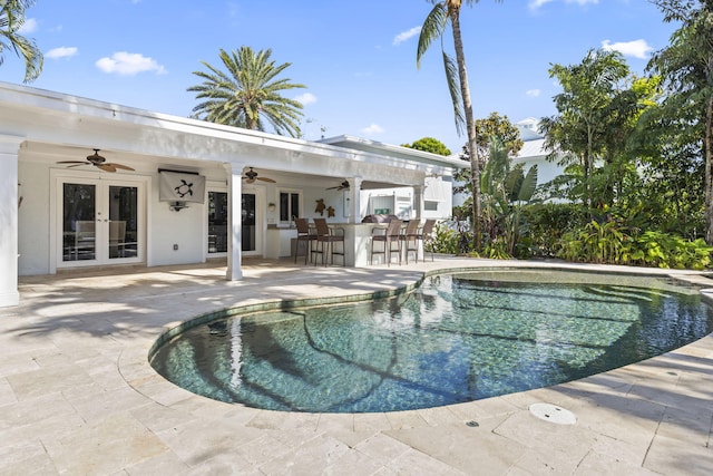 pool with a patio area, french doors, a ceiling fan, and outdoor dry bar