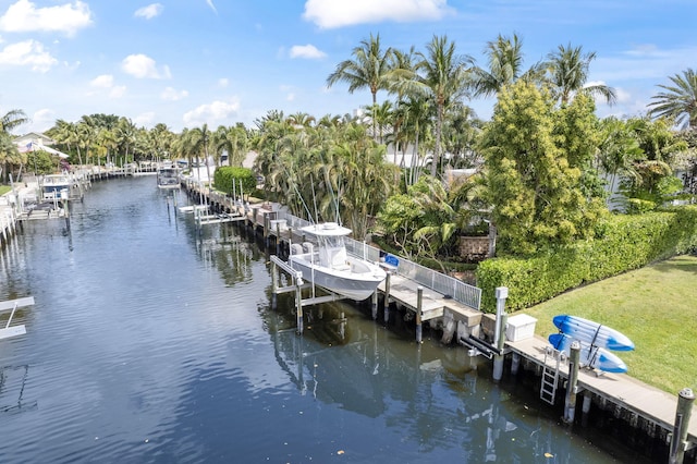 view of dock with a water view, boat lift, and a lawn