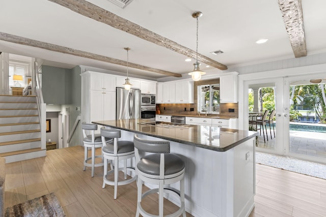 kitchen featuring light wood-style flooring, visible vents, beam ceiling, and appliances with stainless steel finishes