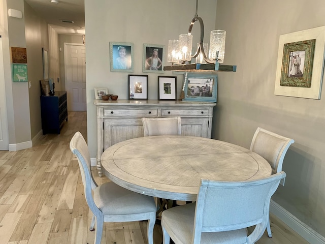 dining room with an inviting chandelier, light wood-style floors, and baseboards