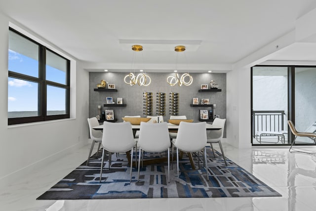 dining area featuring an accent wall, an inviting chandelier, baseboards, and marble finish floor