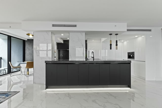 kitchen featuring dark countertops, modern cabinets, marble finish floor, and wall oven