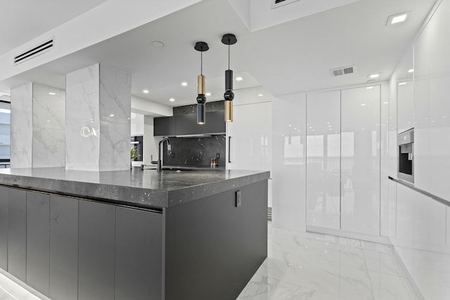 kitchen featuring visible vents, marble finish floor, modern cabinets, a sink, and dark stone countertops